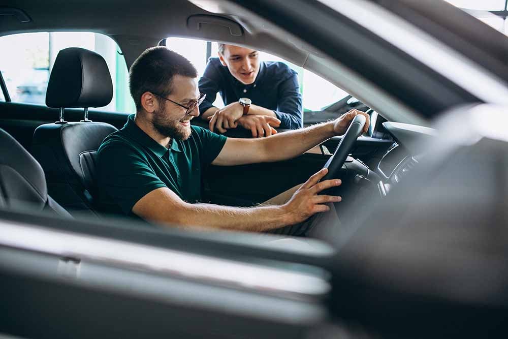 Un jeune homme essaie une voiture dans une salle d'exposition