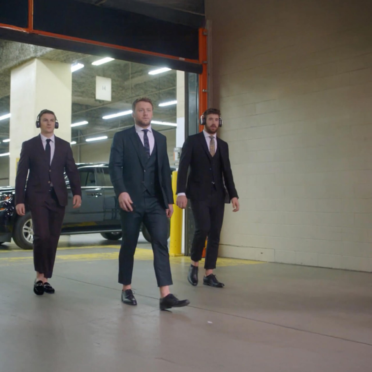 Zach Hyman, Morgan Rielly and Frédérik Gauthier dressed in suits walk from an SUV down a hallway before a hockey game. The Sonnet home and auto logo is on the wall.